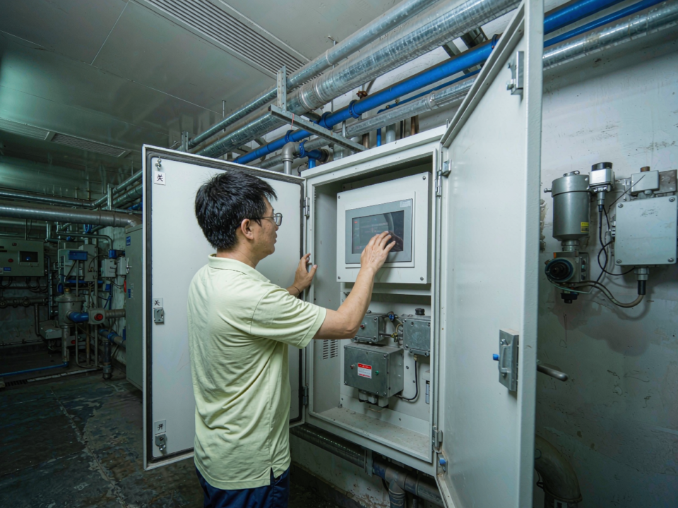 Engineer reviewing water quality readings on an industrial control cabinet in a plant room
